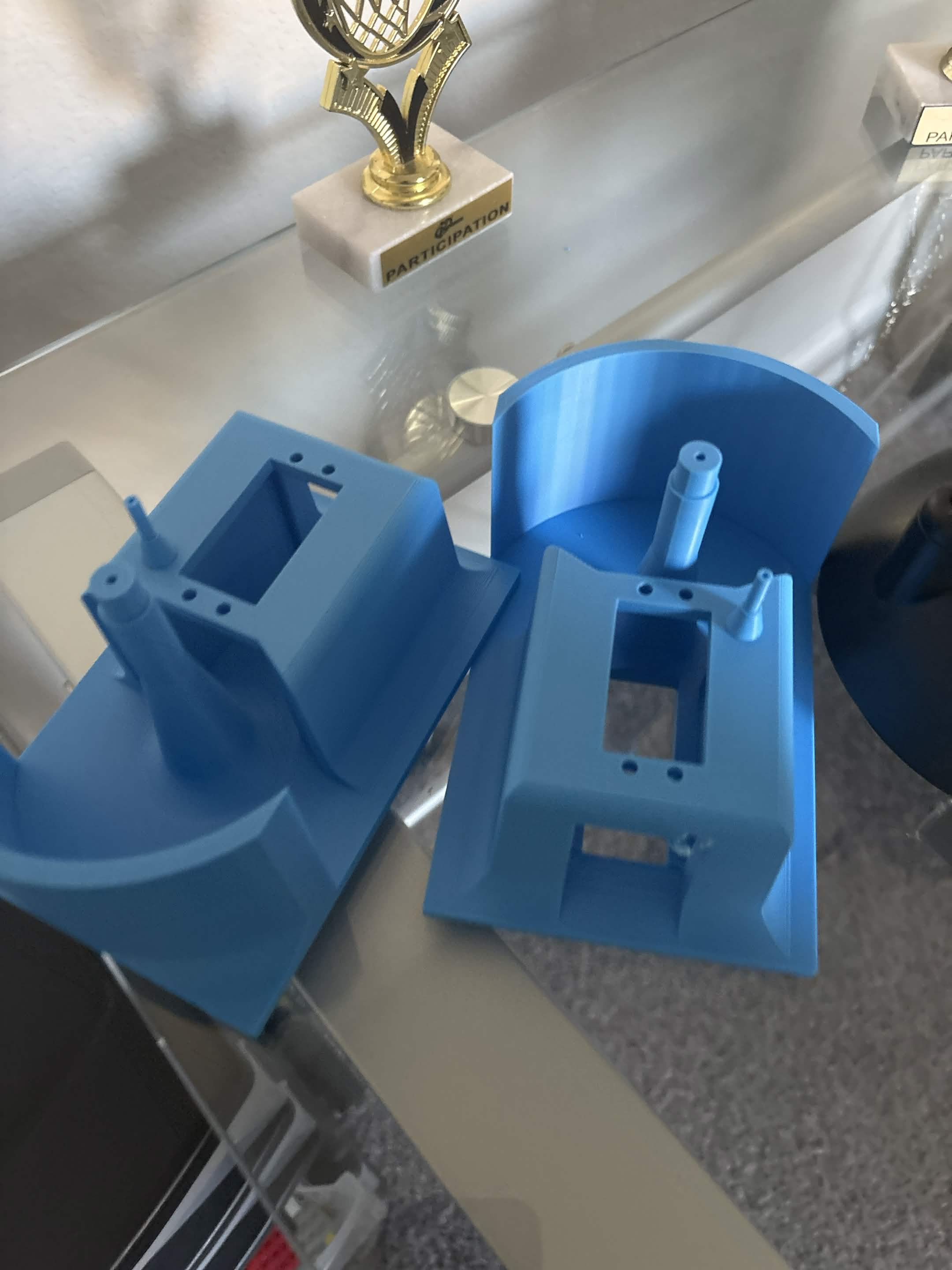 Blue 3D-printed servo housings and curved base walls displayed before assembly