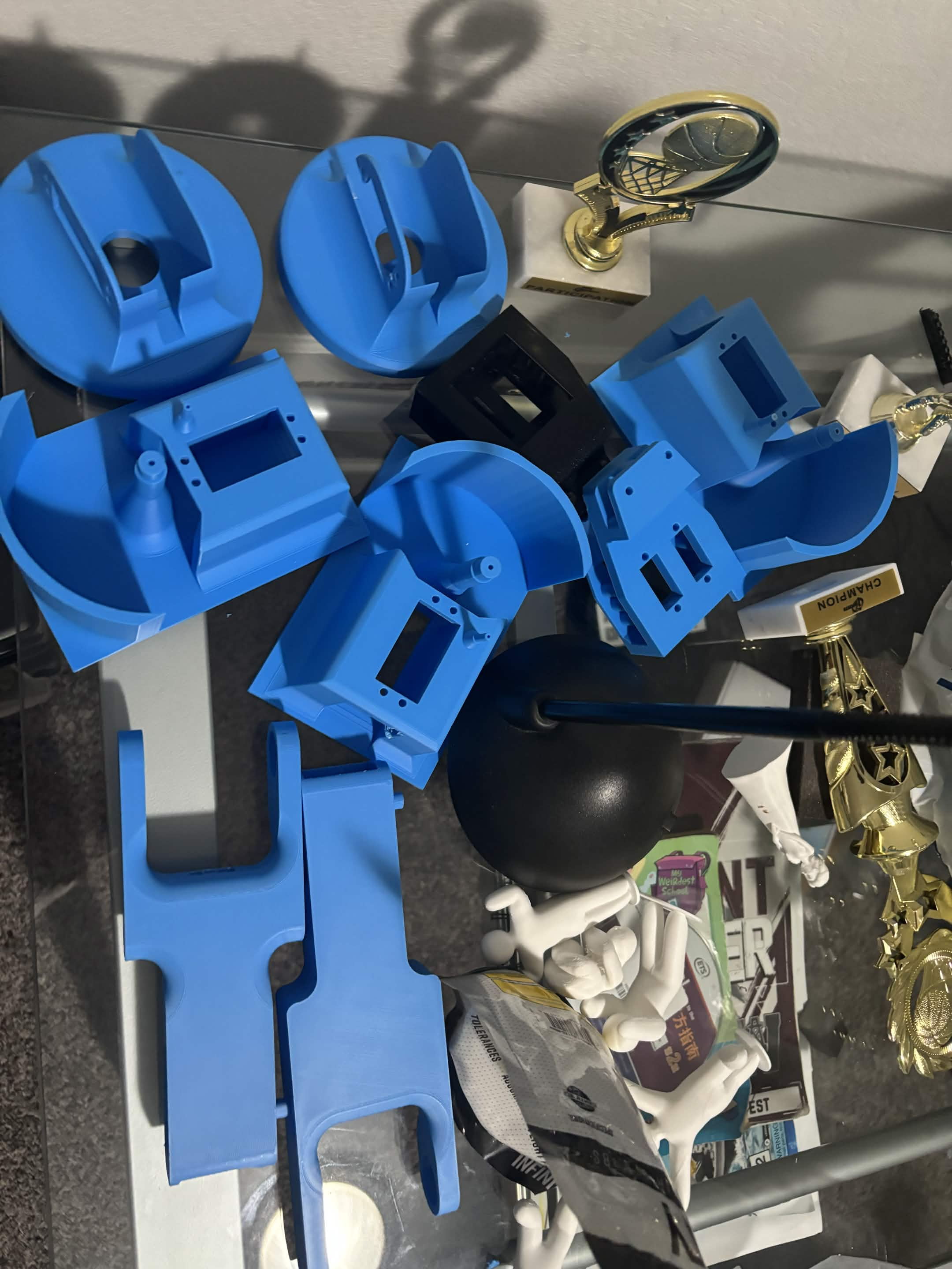 A workbench covered with blue 3D-printed robotic-arm parts, including base housings, brackets, and long arm segments