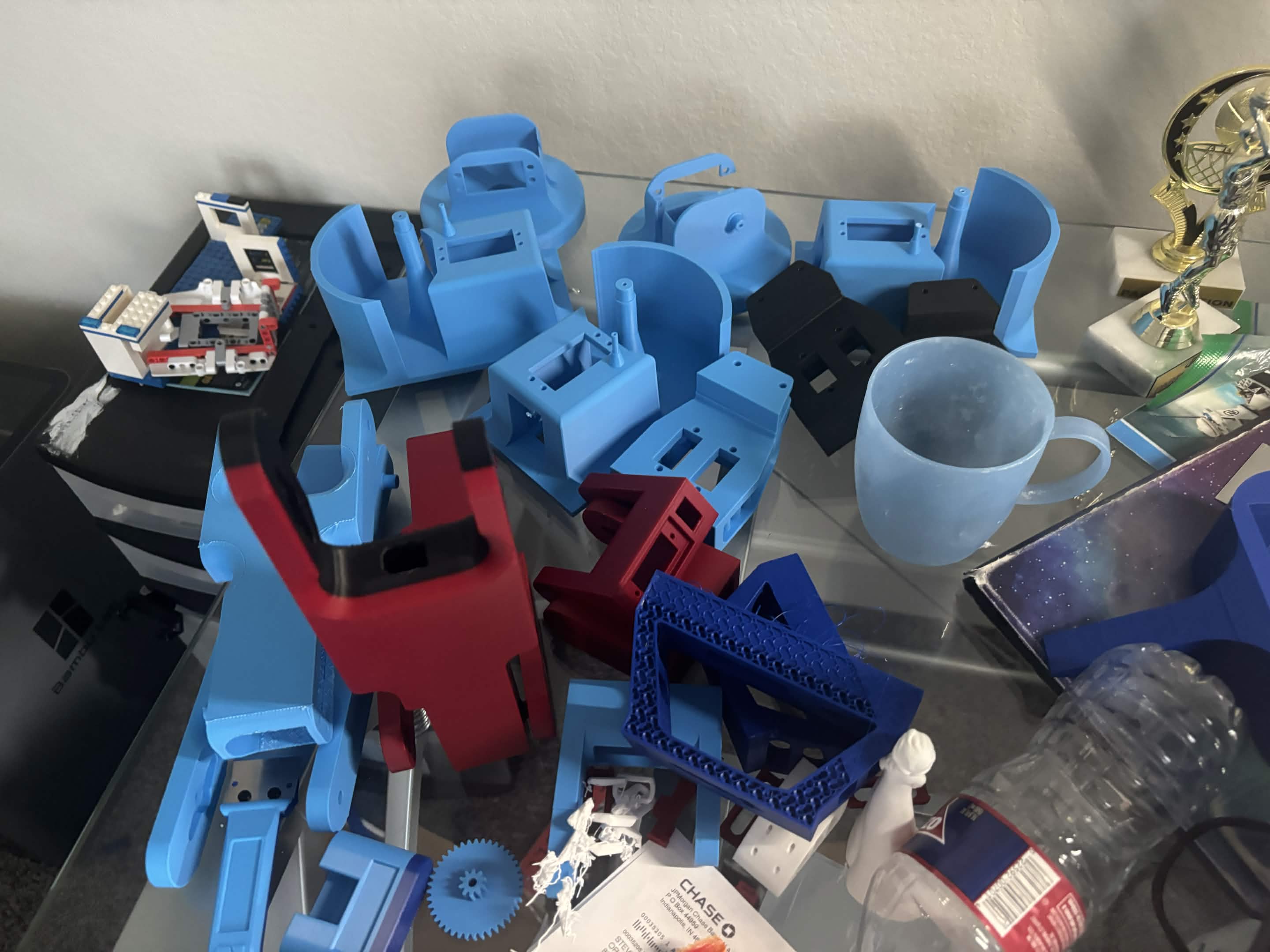 A collection of 3D-printed robotic-arm base parts, brackets, gears, and failed prints