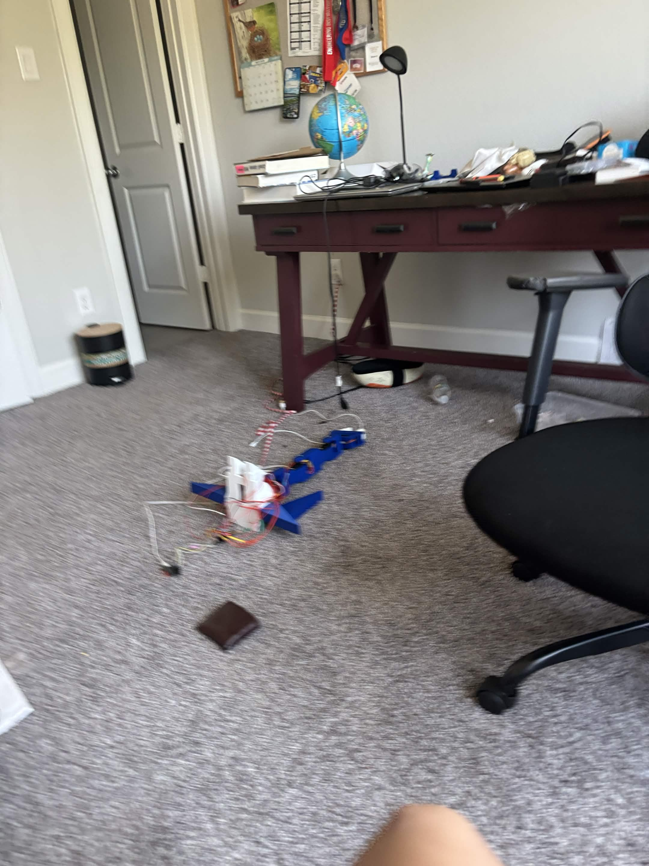Robotic arm lying on a carpeted floor after falling from a table